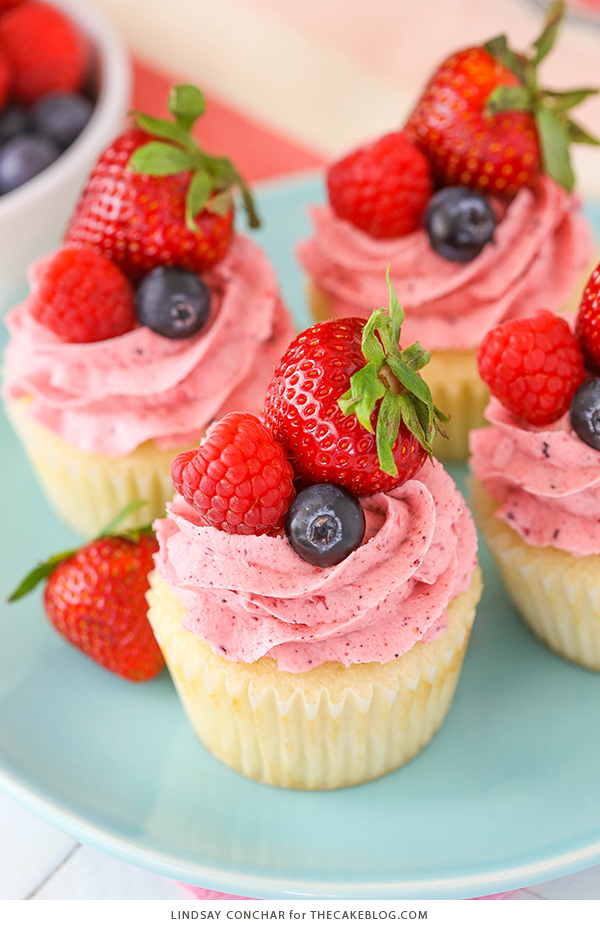 Berries and Cream Cupcakes - mixed berry buttercream paired with a moist vanilla cupcake stuffed with whipped cream cheese filling, topped with fresh strawberries, raspberries and blueberries | by Lindsay Conchar for TheCakeBlog.com
