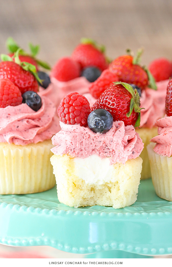Berries and Cream Cupcakes - mixed berry buttercream paired with a moist vanilla cupcake stuffed with whipped cream cheese filling, topped with fresh strawberries, raspberries and blueberries | by Lindsay Conchar for TheCakeBlog.com