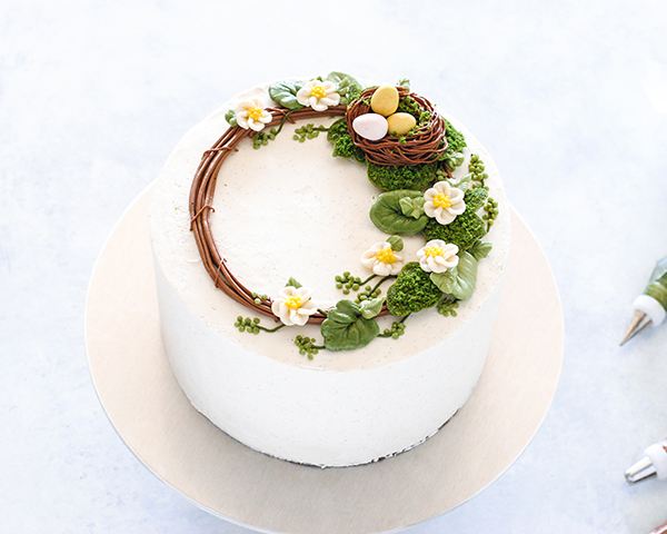 Spring Wreath Cake - how to make a buttercream wreath cake a bird's nest, cherry blossoms, green berries and cookie moss | by Carrie Sellman for TheCakeBlog.com #easter #easterdinnerideas #mothersday #cake