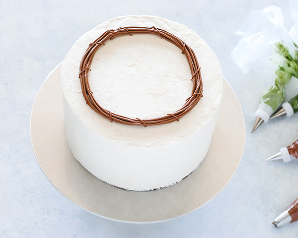 Spring Wreath Cake - how to make a buttercream wreath cake a bird's nest, cherry blossoms, green berries and cookie moss | by Carrie Sellman for TheCakeBlog.com #easter #easterdinnerideas #mothersday #cake