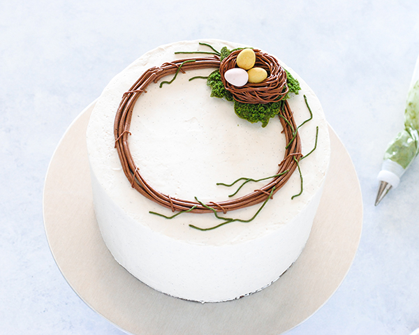 Spring Wreath Cake - how to make a buttercream wreath cake a bird's nest, cherry blossoms, green berries and cookie moss | by Carrie Sellman for TheCakeBlog.com #easter #easterdinnerideas #mothersday #cake