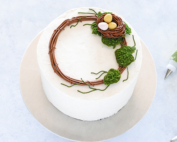 Spring Wreath Cake - how to make a buttercream wreath cake a bird's nest, cherry blossoms, green berries and cookie moss | by Carrie Sellman for TheCakeBlog.com #easter #easterdinnerideas #mothersday #cake