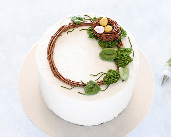 Spring Wreath Cake - how to make a buttercream wreath cake a bird's nest, cherry blossoms, green berries and cookie moss | by Carrie Sellman for TheCakeBlog.com #easter #easterdinnerideas #mothersday #cake