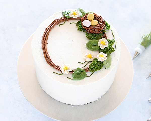 Spring Wreath Cake - how to make a buttercream wreath cake a bird's nest, cherry blossoms, green berries and cookie moss | by Carrie Sellman for TheCakeBlog.com #easter #easterdinnerideas #mothersday #cake