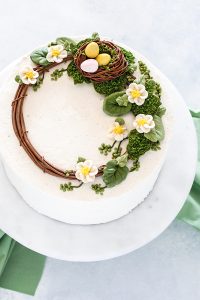 Spring Wreath Cake - how to make a buttercream wreath cake a bird's nest, cherry blossoms, green berries and cookie moss | by Carrie Sellman for TheCakeBlog.com #easter #easterdinnerideas #mothersday #cake